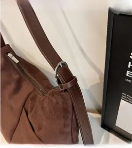 Détail du sac bandoulière en daim café avec boucle argentée et sangle réglable à la main