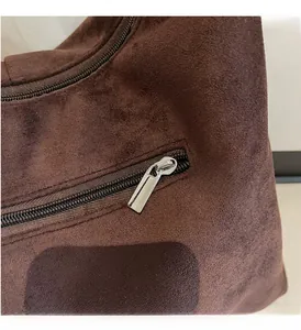 Gros plan détaillé du zip en métal argenté sur la texture du sac cabas en daim marron