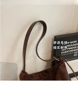 Détail du sac cabas en daim marron avec poignées en cuir renforcées et fermeture éclair