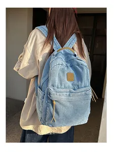 Outdoor shot of light blue denim backpack with brown leather accents and top handle