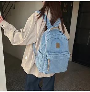 Detail of blue denim backpack with brown leather zipper pulls and side pockets