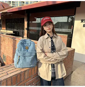 Detail of light blue denim backpack with leather logo patch in a retro campus setting