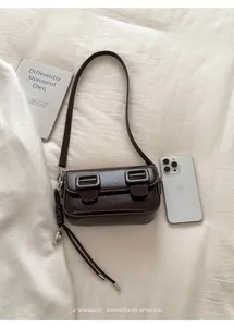 Platliggende vintage donkerbruine vierkante crossbodytas met boeken en telefoon