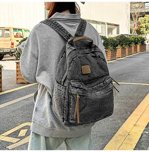 Detailed texture of charcoal grey washed denim backpack with leather embossed logo tag