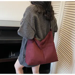 Détail du sac cabas en daim bordeaux montrant la texture douce et les coutures verticales