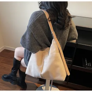 Détail du sac fourre-tout en daim beige avec bandoulière réglable et poche latérale