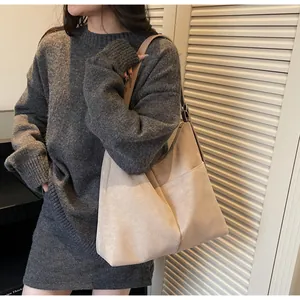Détail du fourre-tout beige montrant la texture mate et la poche sur la bandoulière