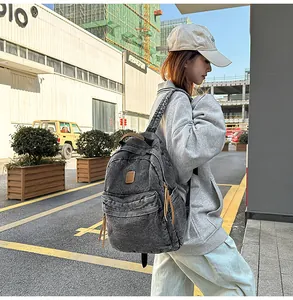 Detail of grey denim backpack showing pleated front pocket and long leather pullers