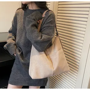 Sac hobo minimaliste en daim beige porté à l'épaule avec bandoulière réglable pratique