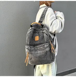 Detail of acid wash denim backpack showing brown leather handle and zip pulls on side view