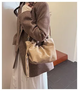 Detail of cream pleated bucket bag showing the metal ring clasp and soft suede texture