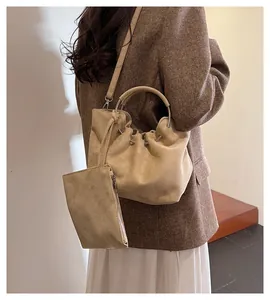 Detail view of khaki pleated bucket bag with metal ring handle and mini zipper pouch