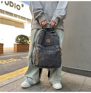 Close-up of a large capacity washed denim backpack with vintage brown leather labels