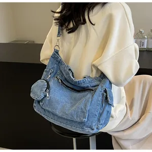 Détail du sac bandoulière en denim délavé avec poches zippées et un petit porte-monnaie
