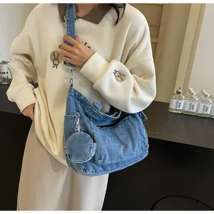 Detail of blue wash denim tote bag showing wide shoulder strap and round coin purse