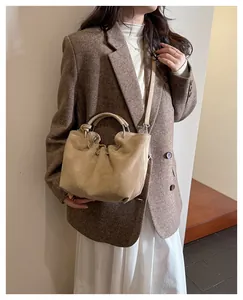 Detail of beige suede cloud bag with metal handle styled in a chic commute outfit