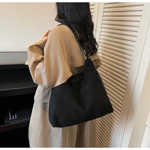 Détail du grand sac hobo minimaliste en daim noir avec bandoulière souple et chic