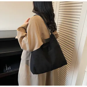 Détail du grand sac cabas noir mat révélant la texture suédée et le drapé souple moderne