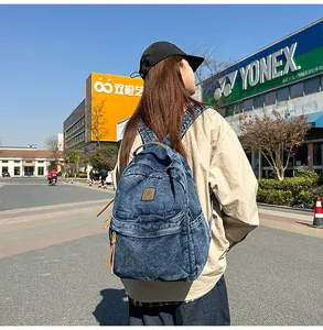 Outdoor shot of a vintage washed blue denim backpack with large capacity and side pockets
