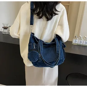 Dettaglio di una borsa tote in denim blu scuro con cuciture e astuccio coordinato