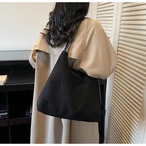 Sac fourre-tout noir minimaliste porté à l'épaule dans un intérieur élégant et moderne