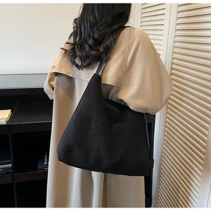 Vue de dos d'un mannequin portant un grand sac hobo en daim noir et un trench-coat