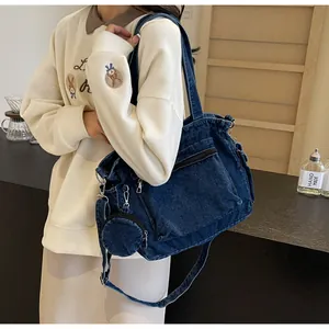 Détail du sac cabas en denim bleu foncé avec multi-poches et mini porte-monnaie accroché