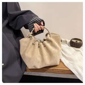 Detail of beige pleated cloud bag in suede fabric with silver metal ring and soft handle
