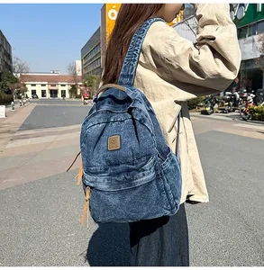 Detail of blue denim backpack with brown leather patch on an urban street background