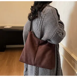 Détail du sac cabas en daim marron foncé avec couture verticale et texture mate élégante