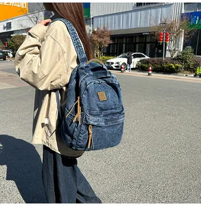 Outdoor shot of a washed denim backpack showing textured fabric and leather pullers