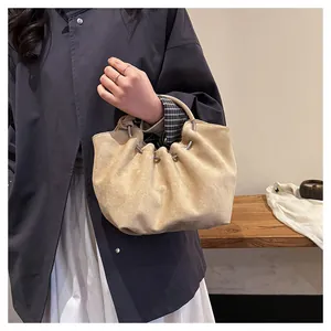 Detail of beige pleated cloud bag with metallic ring handle and soft suede texture