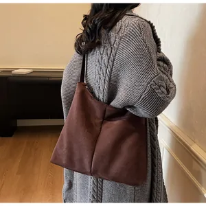 Détail d'un cabas en daim marron foncé avec fermeture éclair sur un pull en maille