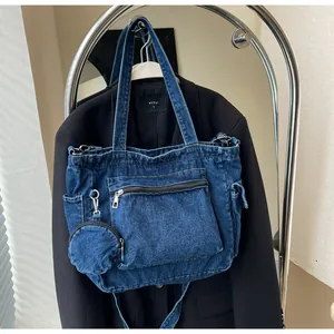 Dettaglio della borsa in denim blu scuro con cerniera frontale e portamonete rotondo
