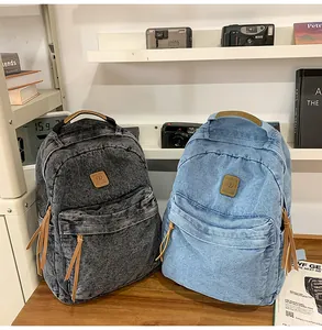 Detail of vintage denim backpacks in dark grey and light blue with leather trim