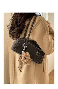 Detail of black leather shoulder bag with white contrast stitching and plush dog charm