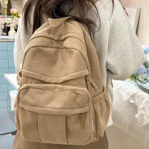 Detailansicht eines khakifarbenen Cord-Rucksacks am Modell in gemütlicher Innenszene