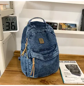 Detail of blue denim backpack with leather patch on wooden desk with vintage camera