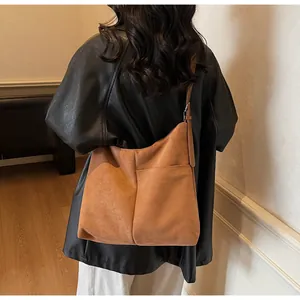 Détail d'un cabas en daim marron avec coutures apparentes et texture mate douce