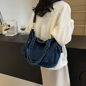 Grand sac cabas en jean bleu foncé avec poches et petit porte-monnaie porté par mannequin