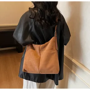 Mannequin portant un sac cabas marron en daim mat montrant sa grande taille et texture