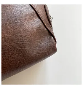 Close-up of deep brown pebbled leather texture with fine stitching and metallic zipper detail