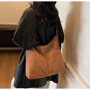 Vue détaillée du grand sac cabas en daim marron avec poche avant et fine bandoulière