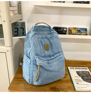 Close-up of vintage light blue denim backpack with brown leather strap and front pocket