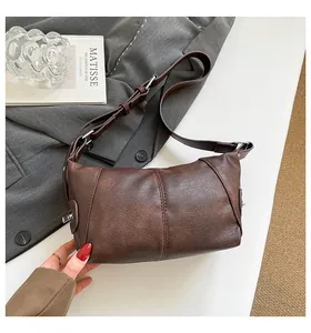 Detail of dark brown retro shoulder bag with leather patchwork and silver hardware