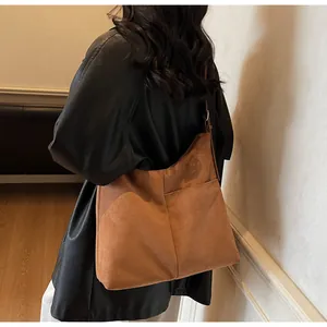 Détail d'un sac cabas en daim marron avec une poche latérale pratique et une texture douce