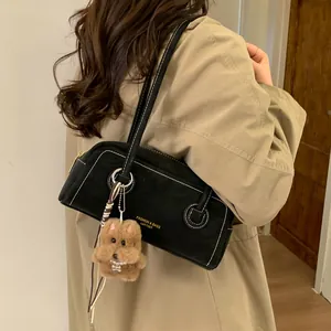 Chic black baguette bag with white contrast stitching and a plush bear charm detail