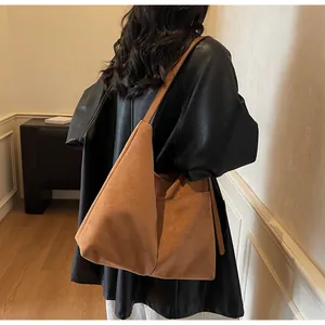 Détail d'un grand sac cabas en daim marron montrant la texture et la tenue de la bandoulière