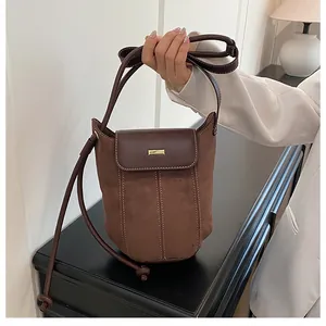 Detail of vintage brown bucket bag showing suede and smooth leather splicing with gold hardware