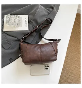 Detail view of deep brown lychee texture leather handbag with adjustable buckle strap